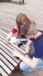 Uczniowie rozwiązują zadanie korzystając z aplikacji na telefonie.