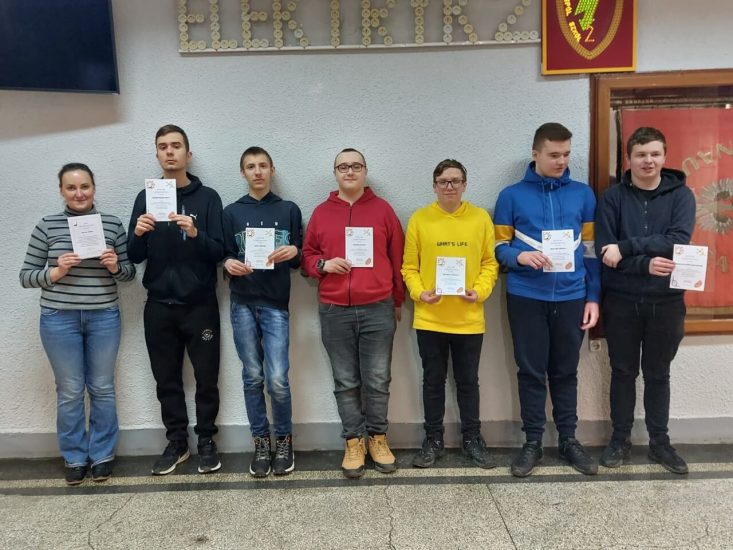 6 uczniów z opiekunka stoi w holu szkoły pod napisem Elektryk2. 