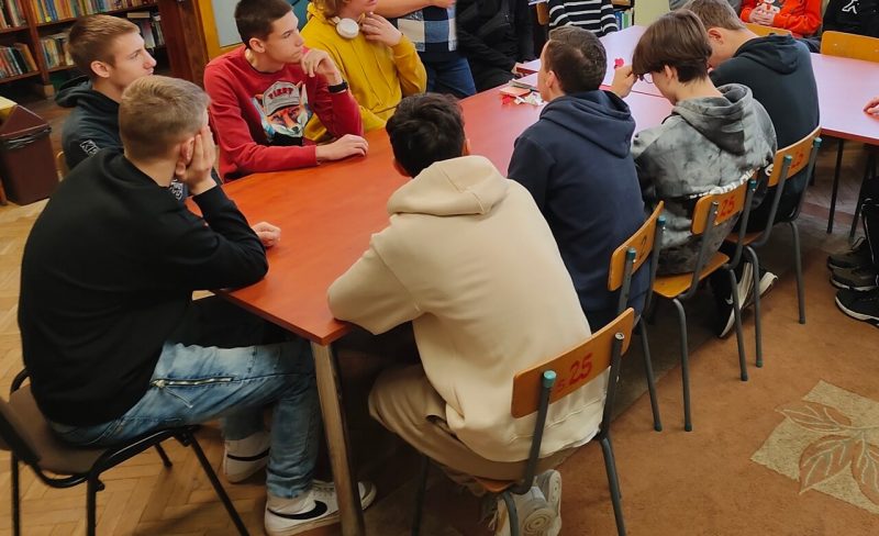 Grupa uczniów podczas zajęć w czytelni szkolnej. 