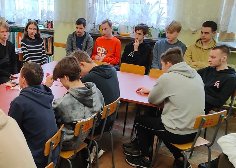 Grupa uczniów podczas zajęć w czytelni szkolnej. 