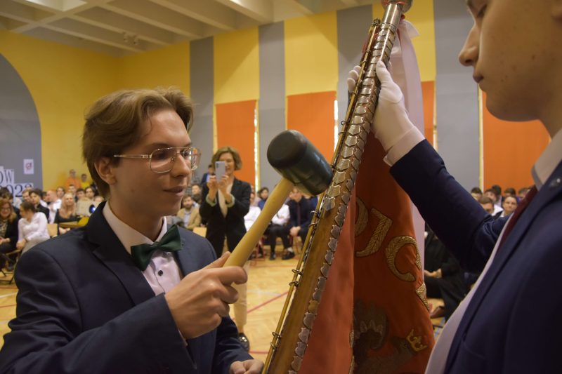 Najlepszy absolwent wbija gwóźdź w drzewce sztandaru