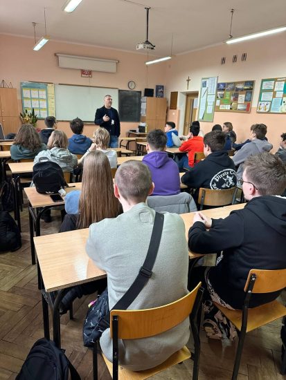 uczniowie w sali lekcyjnej słuchają prowadzącego prelekcje